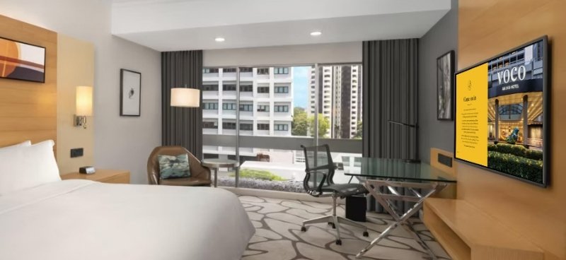 A voco Orchard Singapore guest room with a branded welcome screen on the in-room TV
